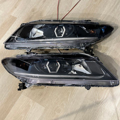 Pair of car headlight assemblies on a wooden surface